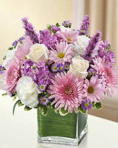<p>This bouquet features a lavender and white arrangement of roses, stock, liatris, cremones, carnations, daisy poms and monte casino, accented with variegated pittosporum<br />
artistically designed by our florists in a classic clear glass cube vase lined with a Ti leaf ribbon.</p>